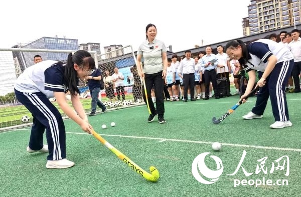 陳朝霞（中）指導(dǎo)學(xué)生體驗曲棍球。 人民網(wǎng)記者 楊磊攝